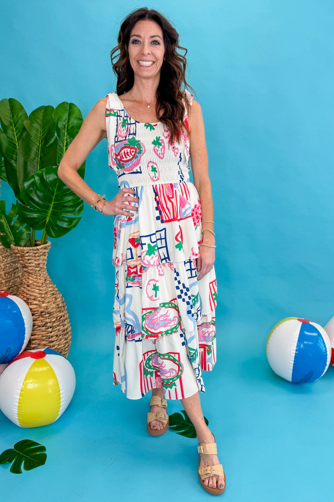 Front view of woman wearing Multi Printed Tiered Midi Dress against blue beachy background.