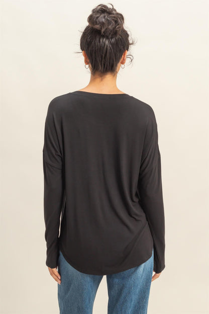 Person wearing a black long-sleeve top and blue jeans on a beige background