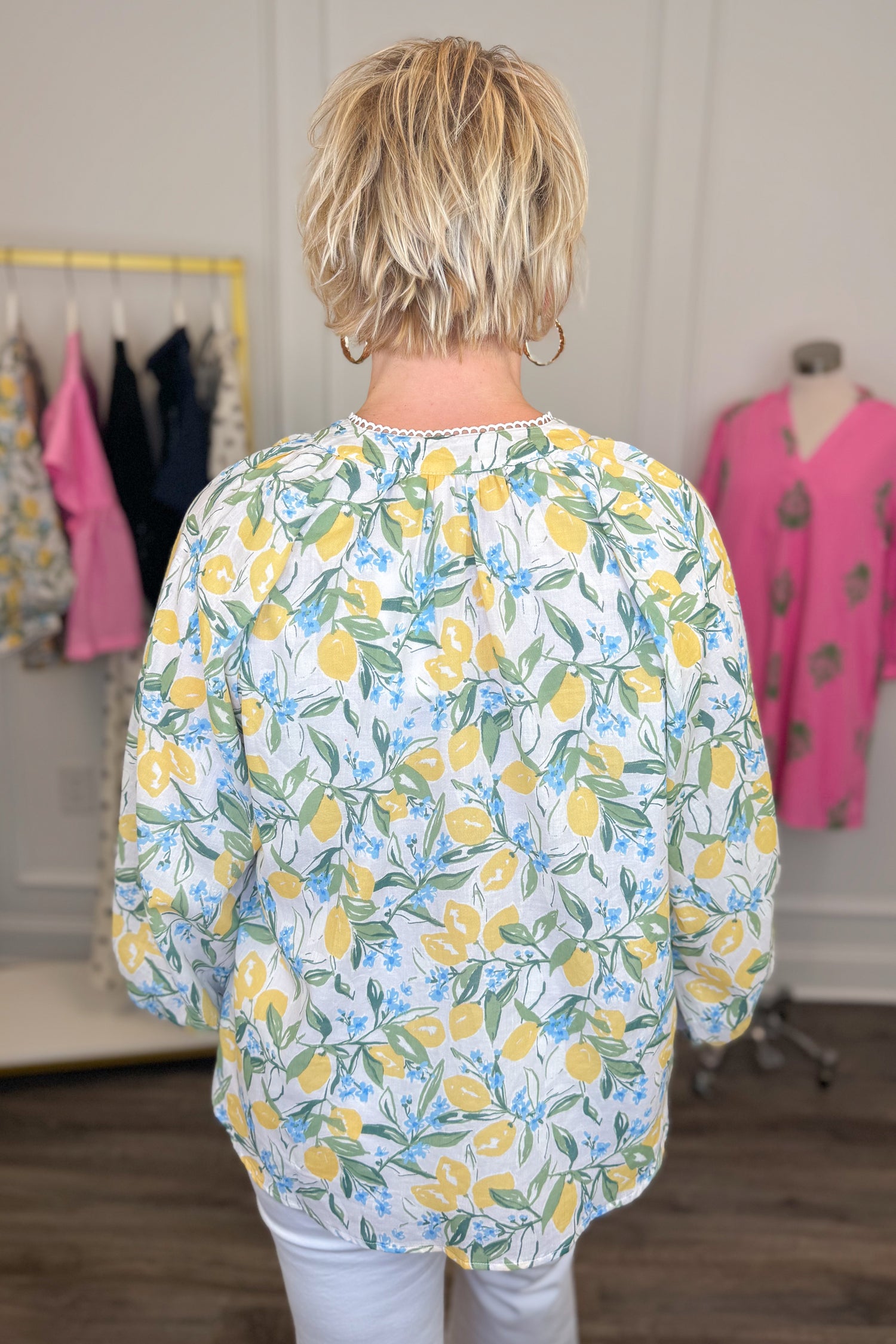 Back view of woman wearing Swagger Boutique’s Yellow &amp; Blue Lemon Print 3/4 Sleeve Top with jeans with clothes around.