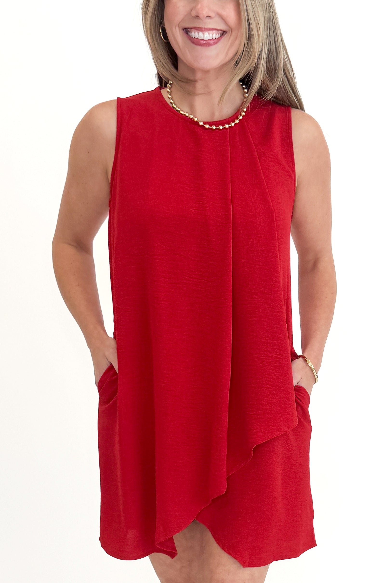 Front detail view of woman wearing Red Pleat Detail Shift Dress against white studio background.