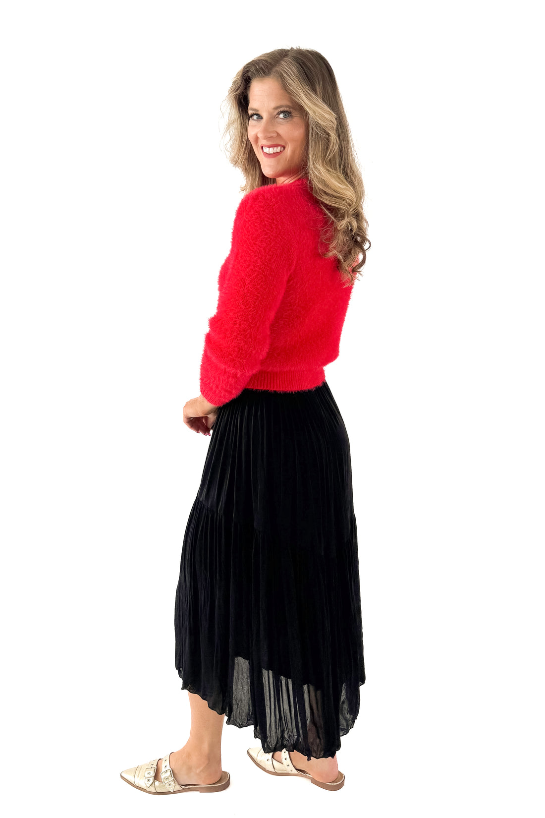 Side view of woman wearing red sweater with black skirt against white studio background.