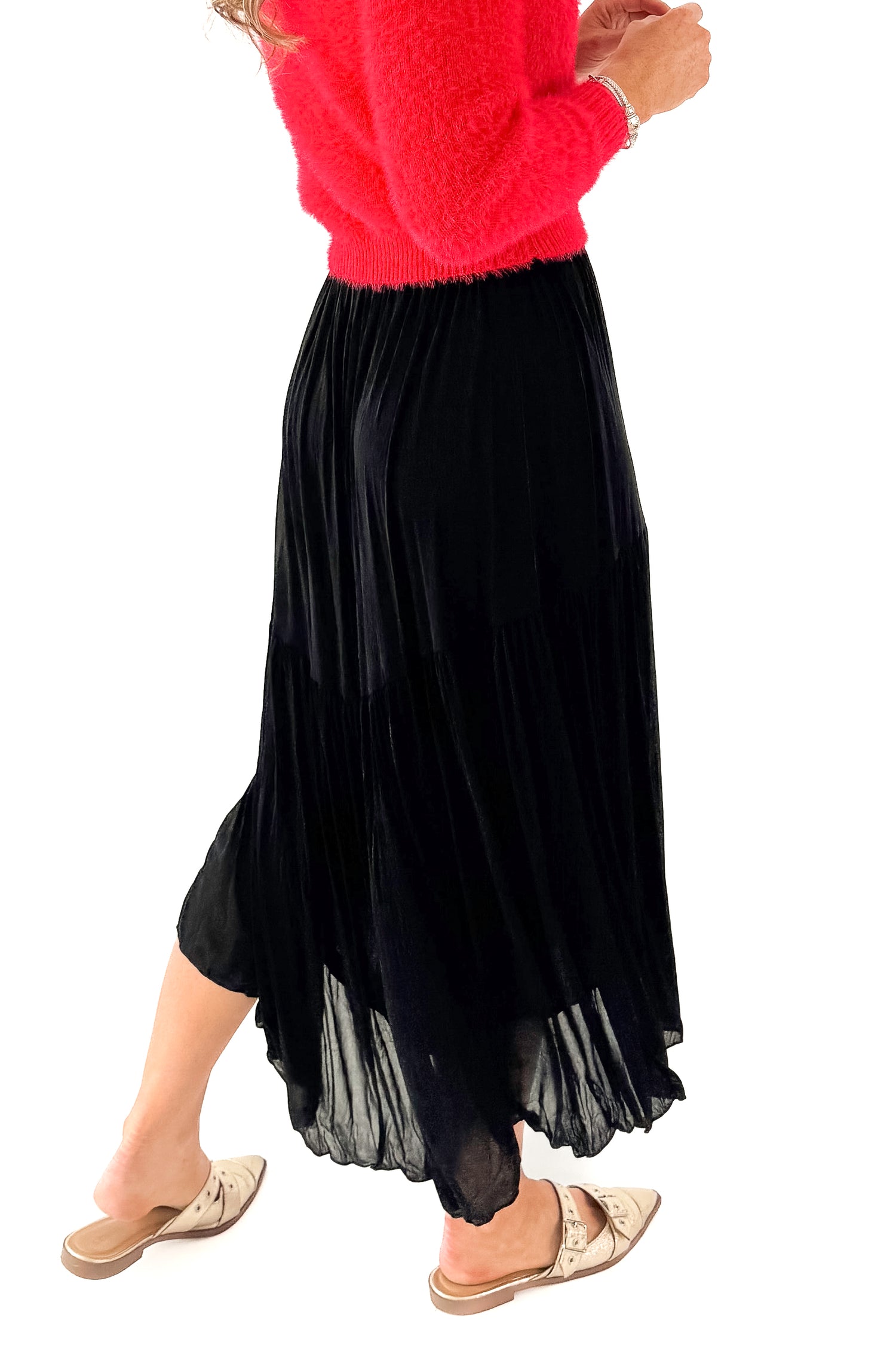 Side detailed view of woman wearing red sweater with black skirt against white studio background.