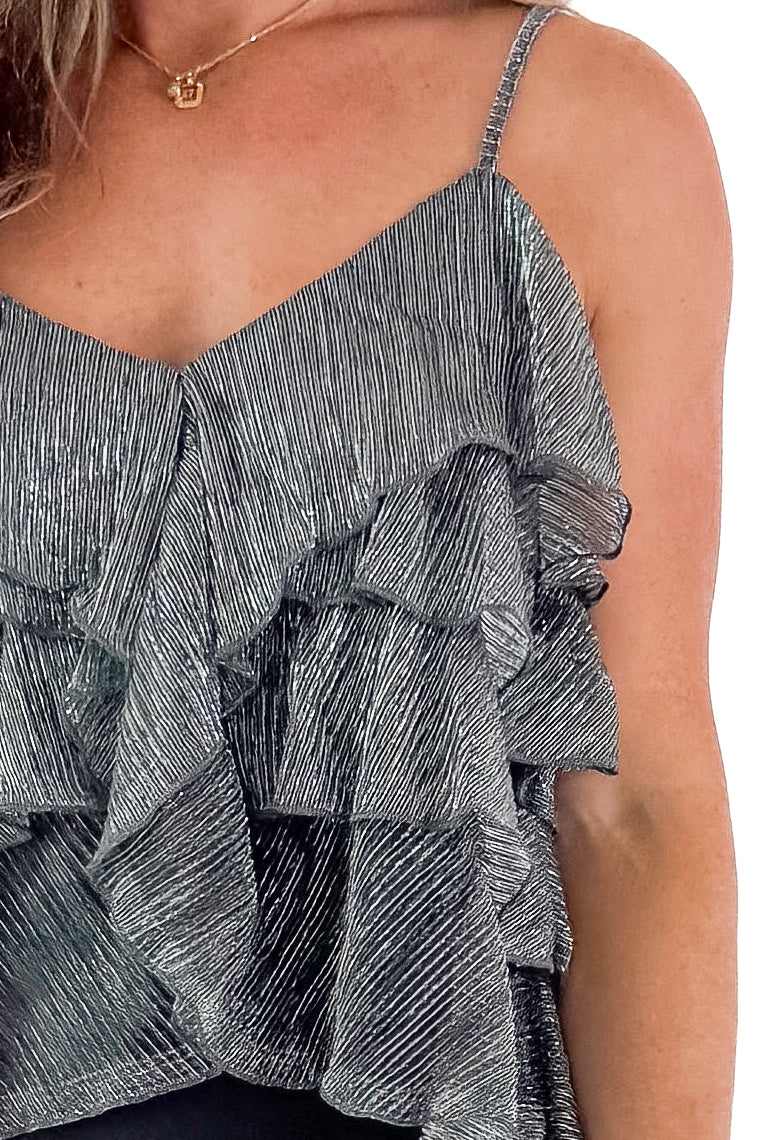 Front detailed view of woman wearing Silver Metallic Ruffle Tank with black skirt against white studio background.