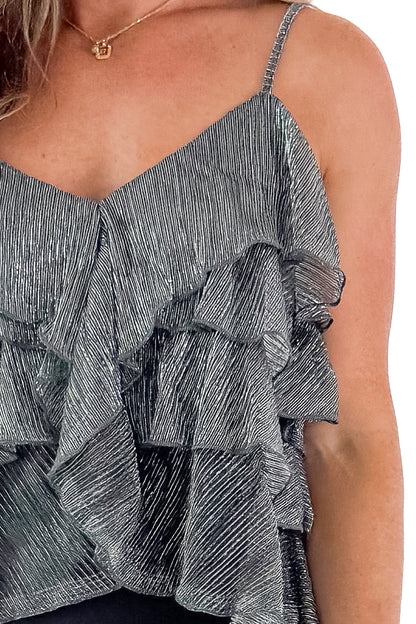 Front detailed view of woman wearing Silver Metallic Ruffle Tank with black skirt against white studio background.