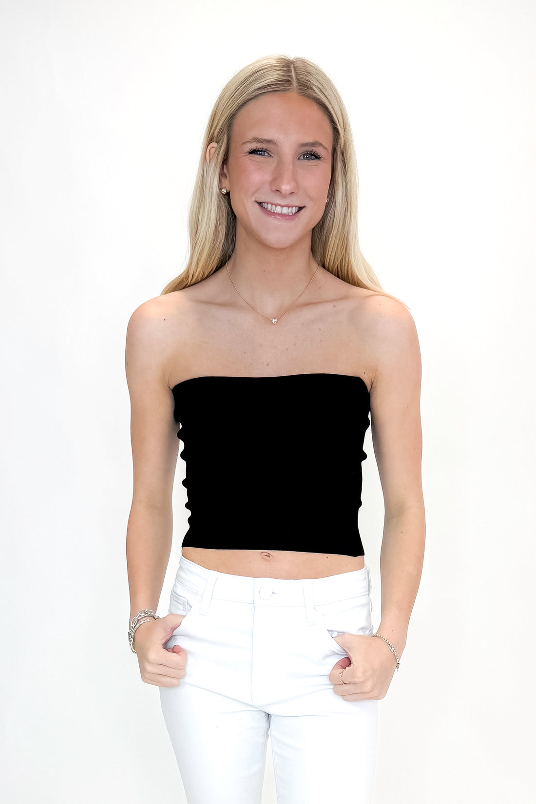 Front view of woman wearing Black Ribbed Tube Top with jeans against white studio background.