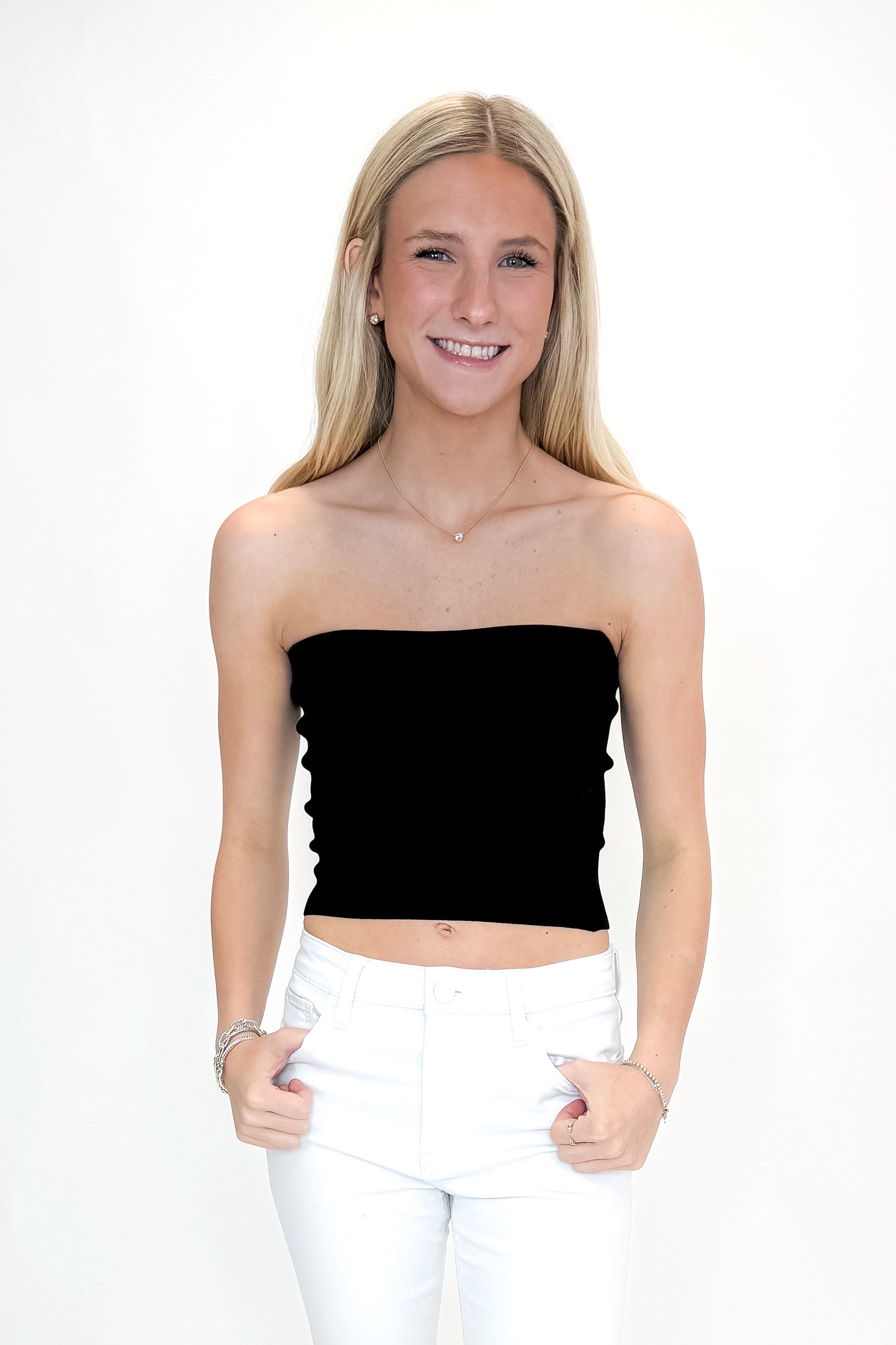 Front view of woman wearing Black Ribbed Tube Top with jeans against white studio background.