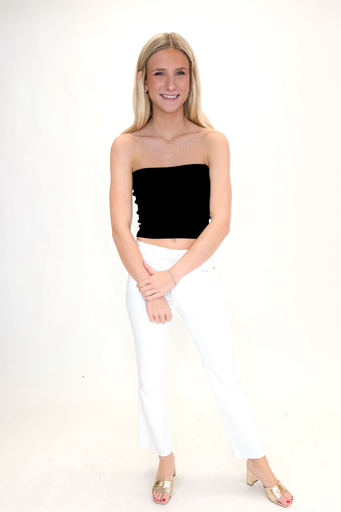 Front view of woman wearing Black Ribbed Tube Top with jeans against white studio background.