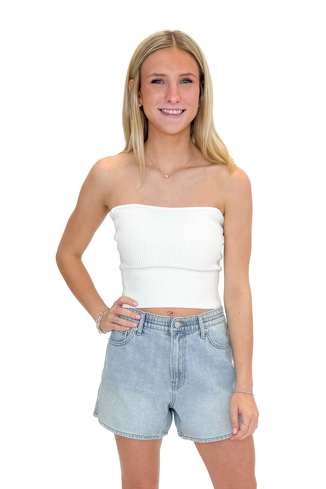 Front view of woman wearing Off White Ribbed Tube Top with jean shorts against white studio background.