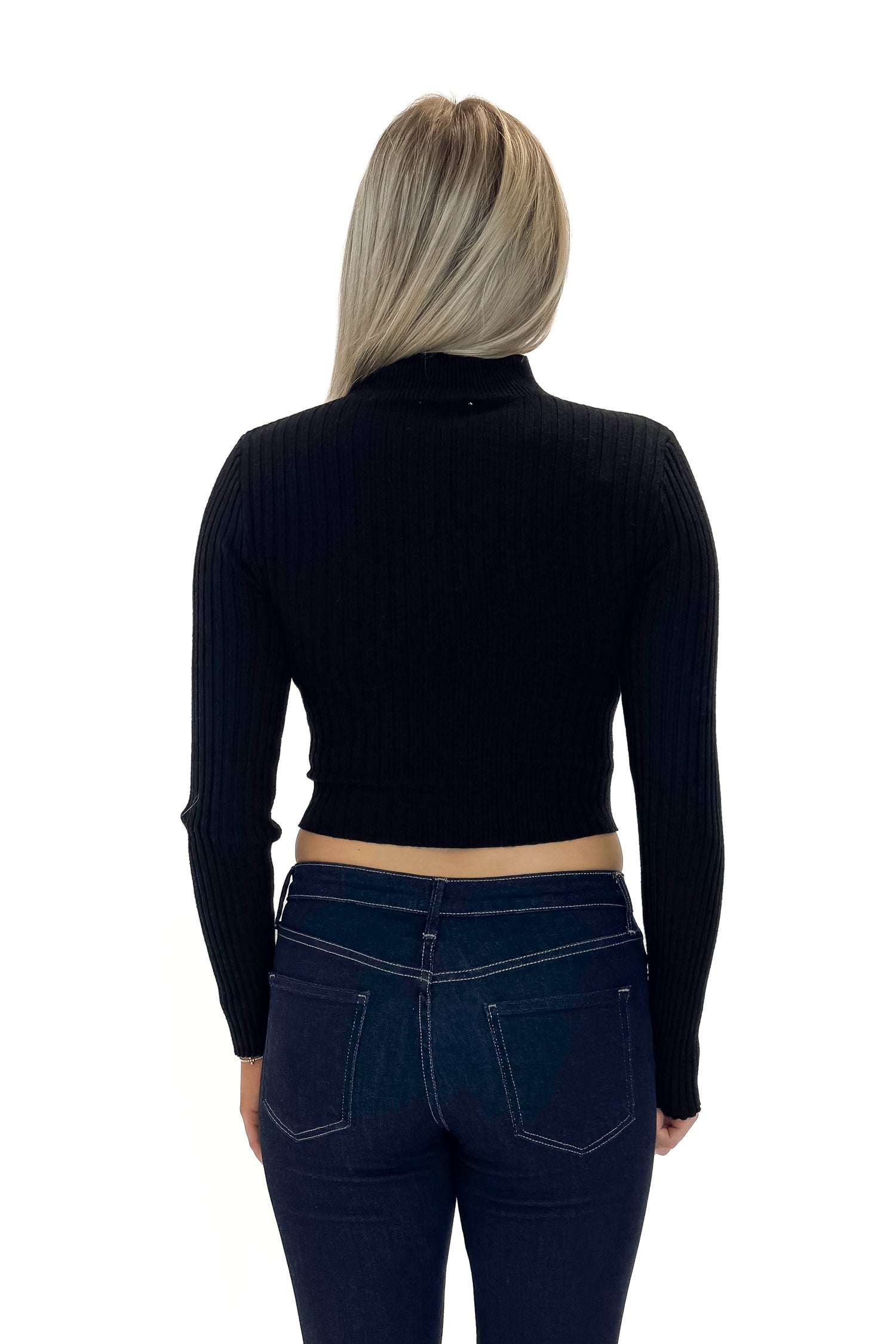 Back view of woman wearing Black Ribbed Asymmetrical Top with jeans against white studio background.