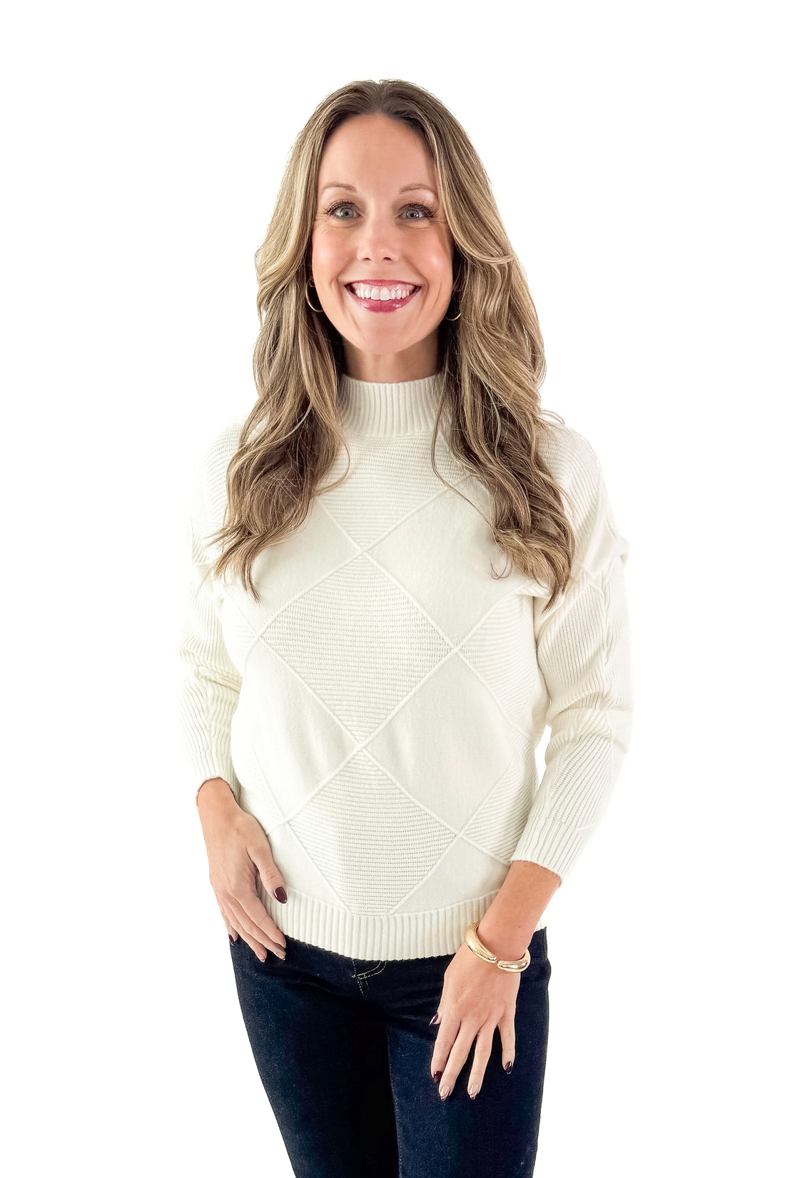 Front view of woman wearing Cream Diamond Mock Neck Sweater with jeans against white studio background