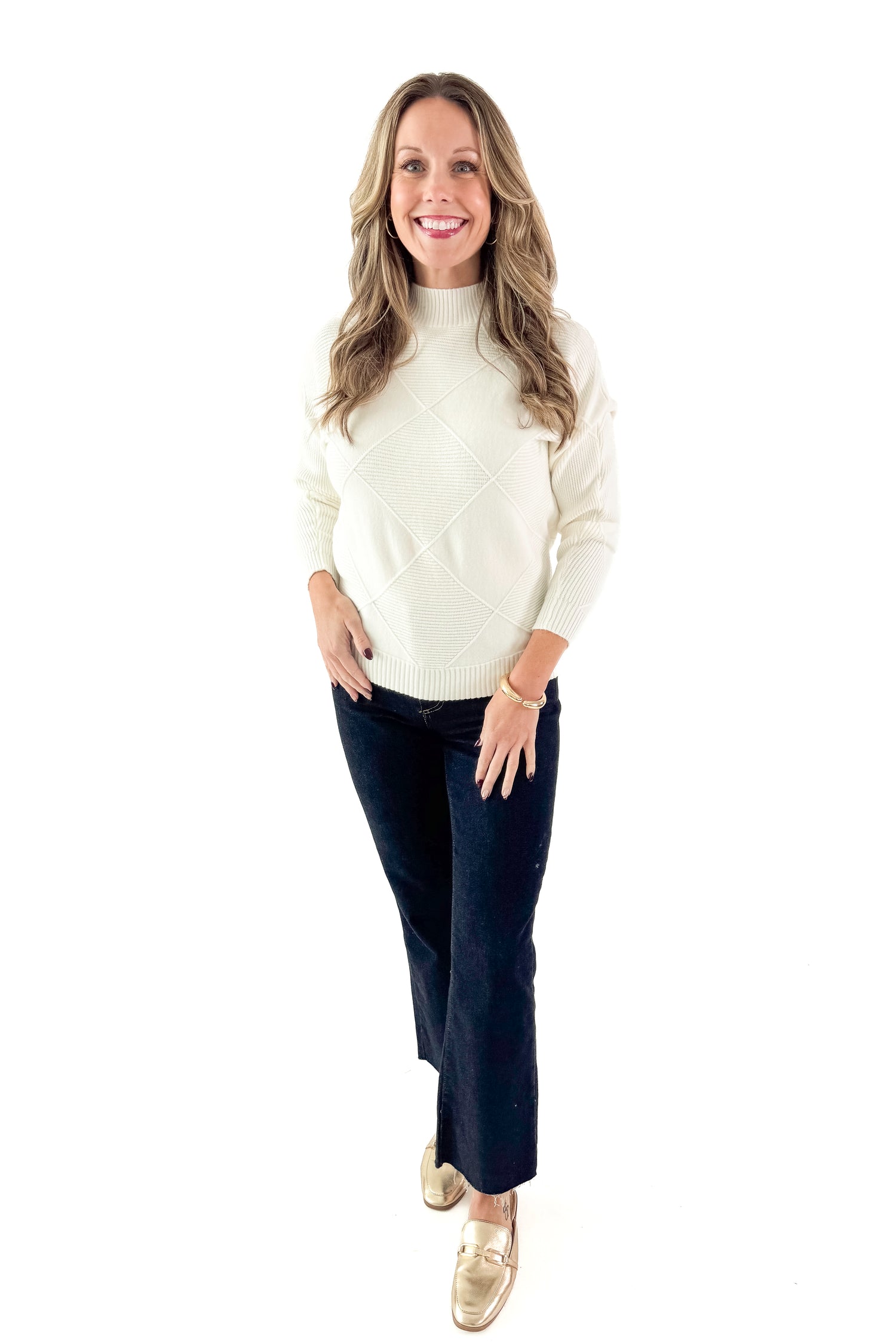 Front view of woman wearing Cream Diamond Mock Neck Sweater with jeans against white studio background