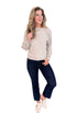 Studio picture of woman wearing Oat Cable Knit Dolman Sweater and jeans with white background.