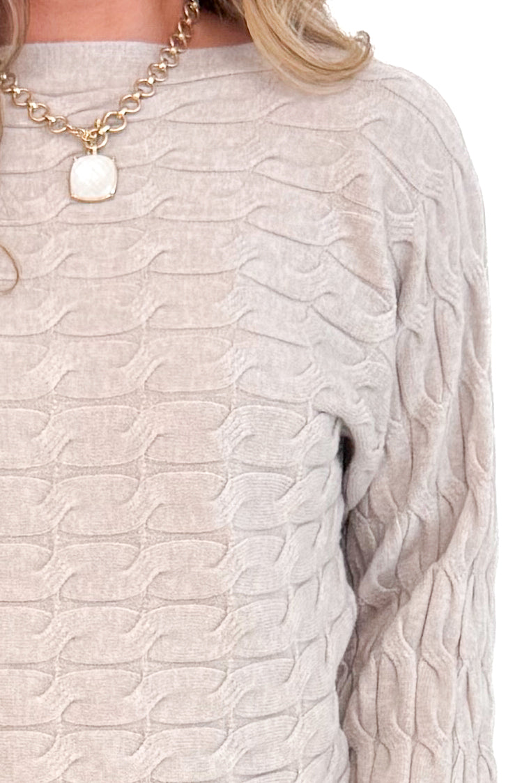 Detailed view of Oat Cable Knit Dolman Sweater with white background.