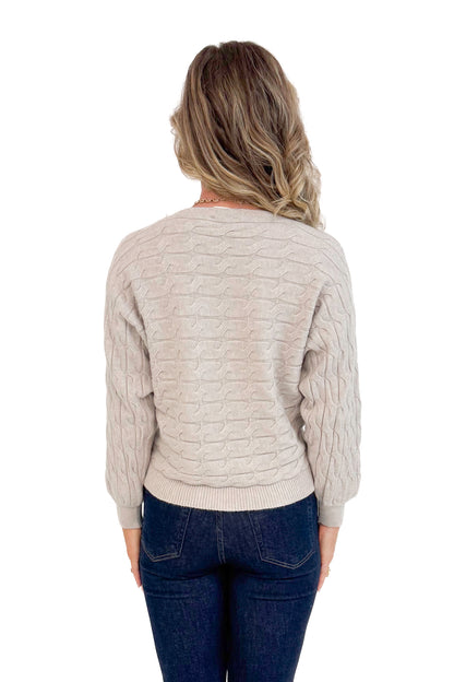 Studio back picture of woman wearing Oat Cable Knit Dolman Sweater and jeans with white background.