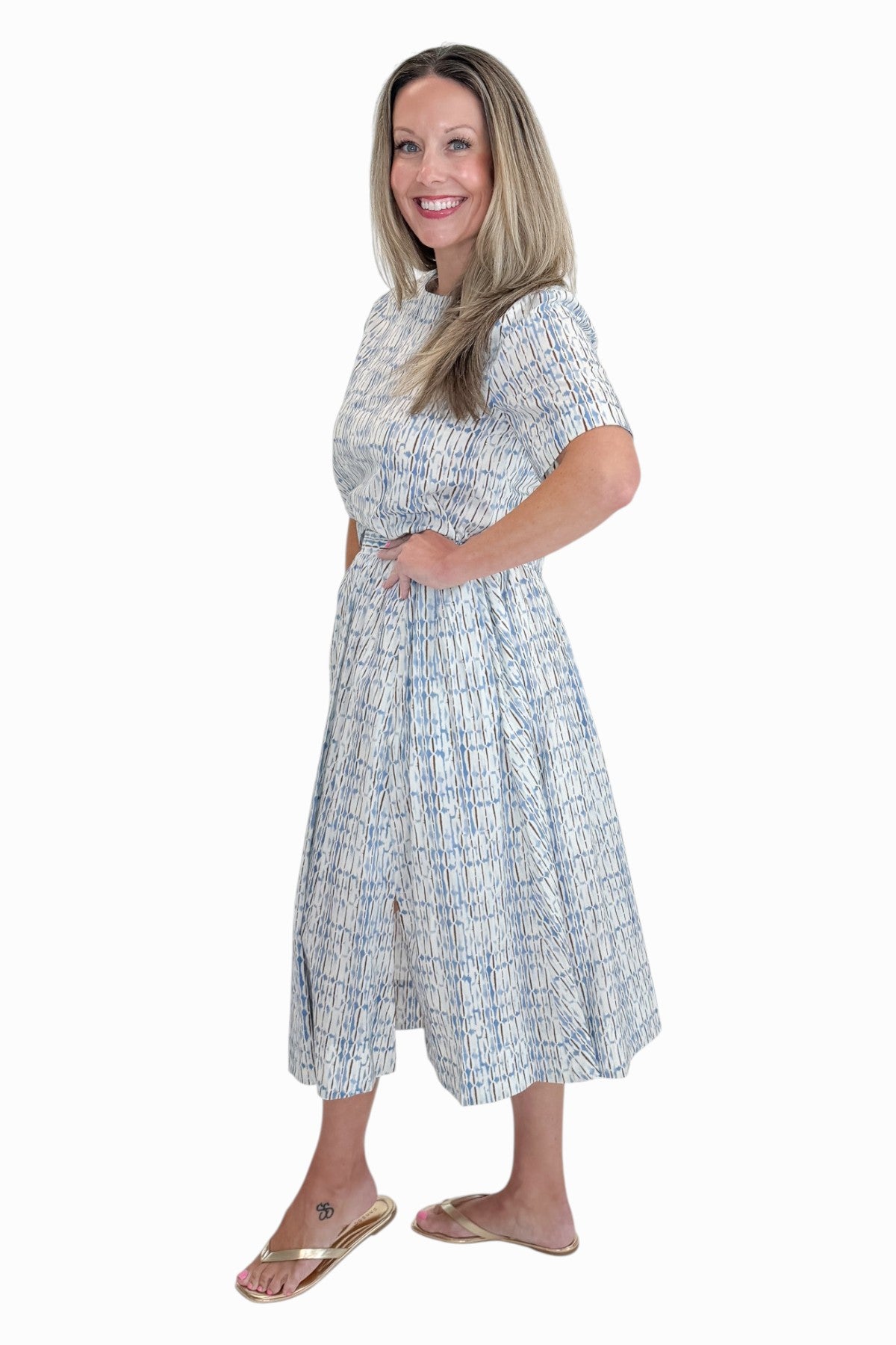 Side view of woman wearing Swagger Boutique’s Blue &amp; Brown Abstract Print Short Sleeve Top with matching skirt against white studio background.