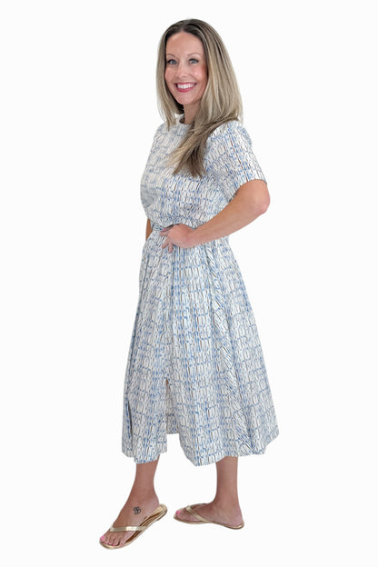 Side view of woman wearing Swagger Boutique’s Blue &amp; Brown Abstract Print Short Sleeve Top with matching skirt against white studio background.