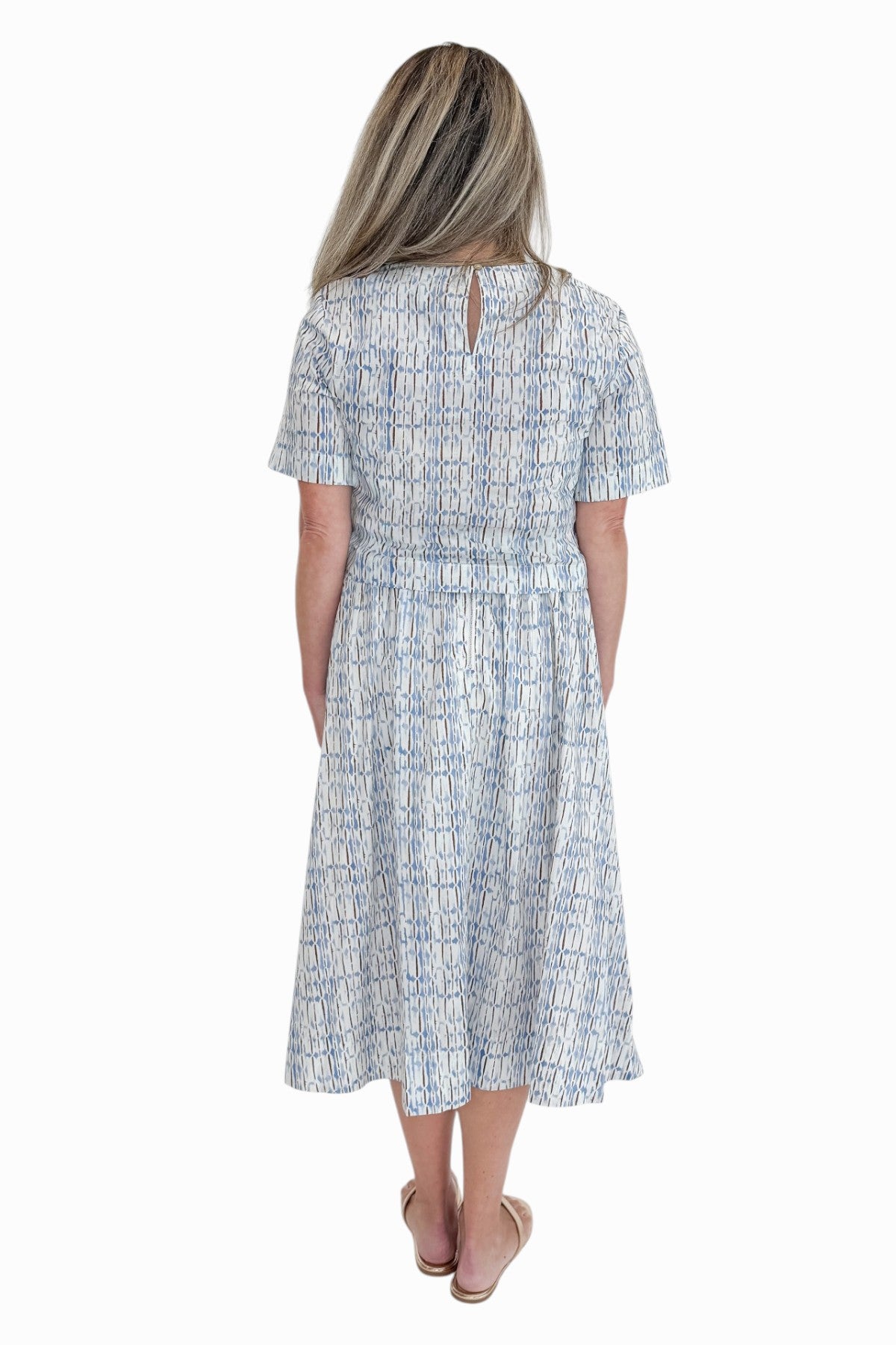 Back view of woman wearing Swagger Boutique’s Blue &amp; Brown Abstract Print Short Sleeve Top with matching skirt against white studio background.
