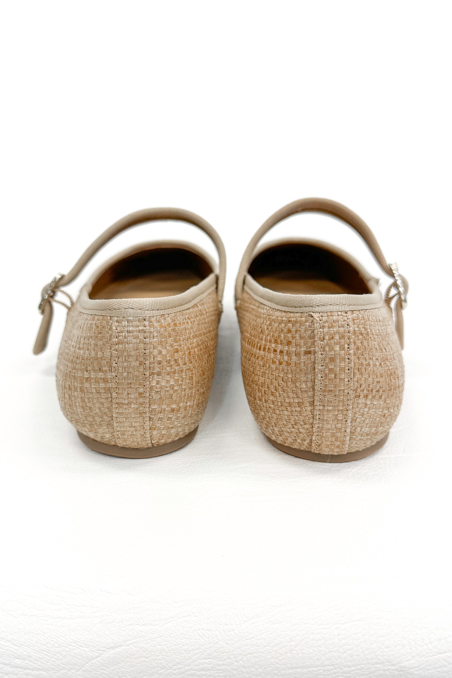 Adora- Natural Raffia Flats against white studio background back view.