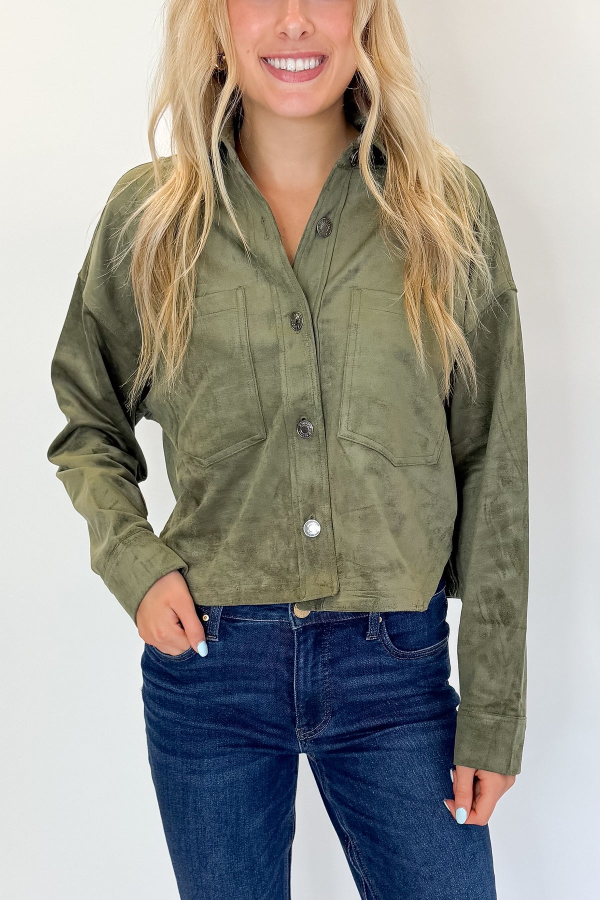 Front detail view of woman wearing Swagger Boutique’s Monstera All Day Cropped Suede Jacket by Z Supply with jeans against white studio background.