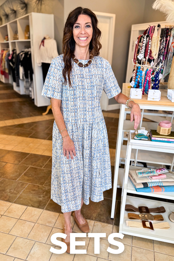 front view of woman wearing a blue and brown abstract short sleeve top paired with the matching midi skirt and photo says Sets at the bottom 