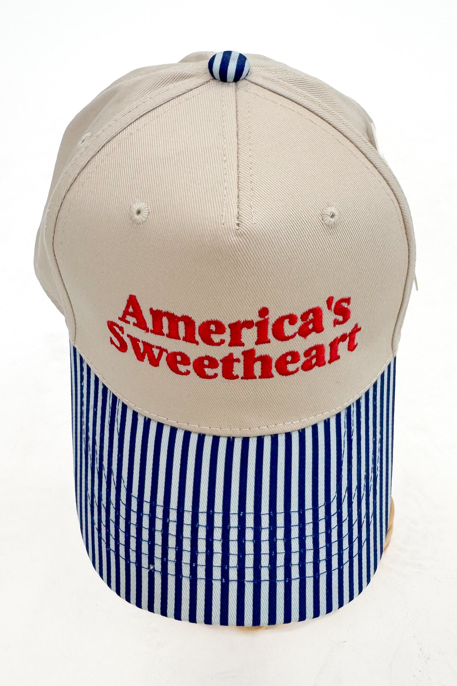 Top view of trucker hat showing the crown shape, stitching, and striped brim. 