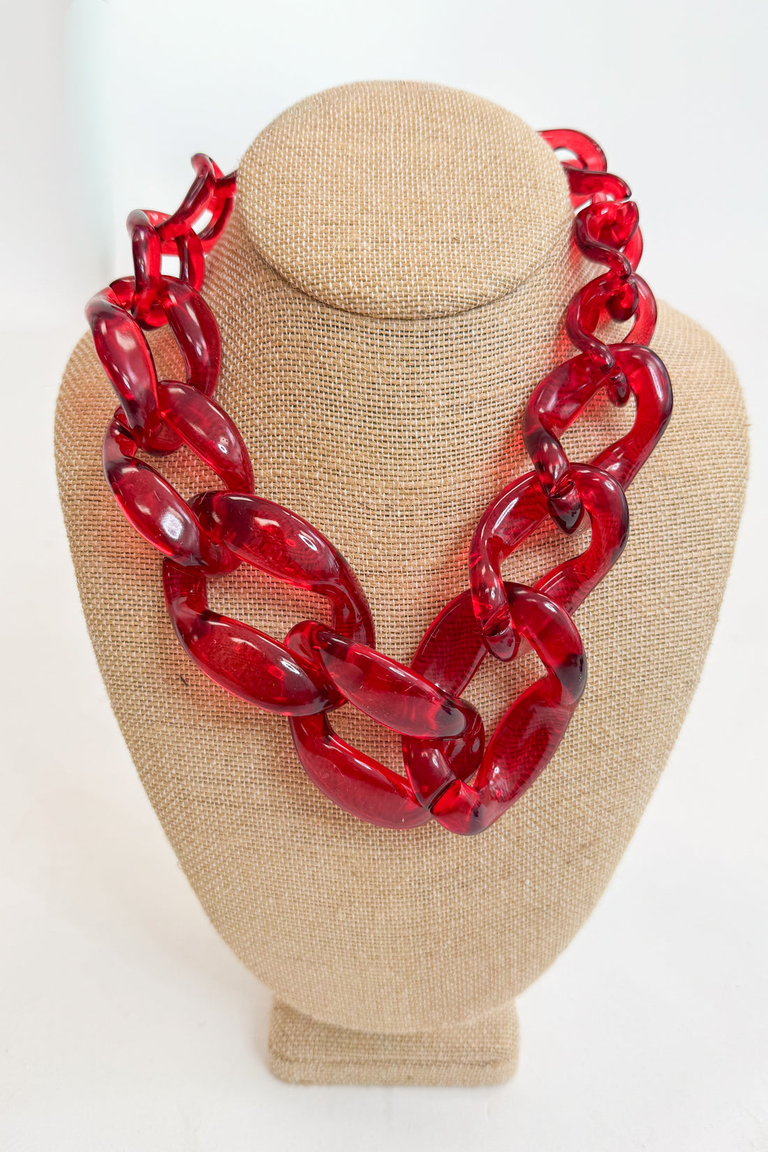 Red chain necklace on a beige mannequin bust against a white background