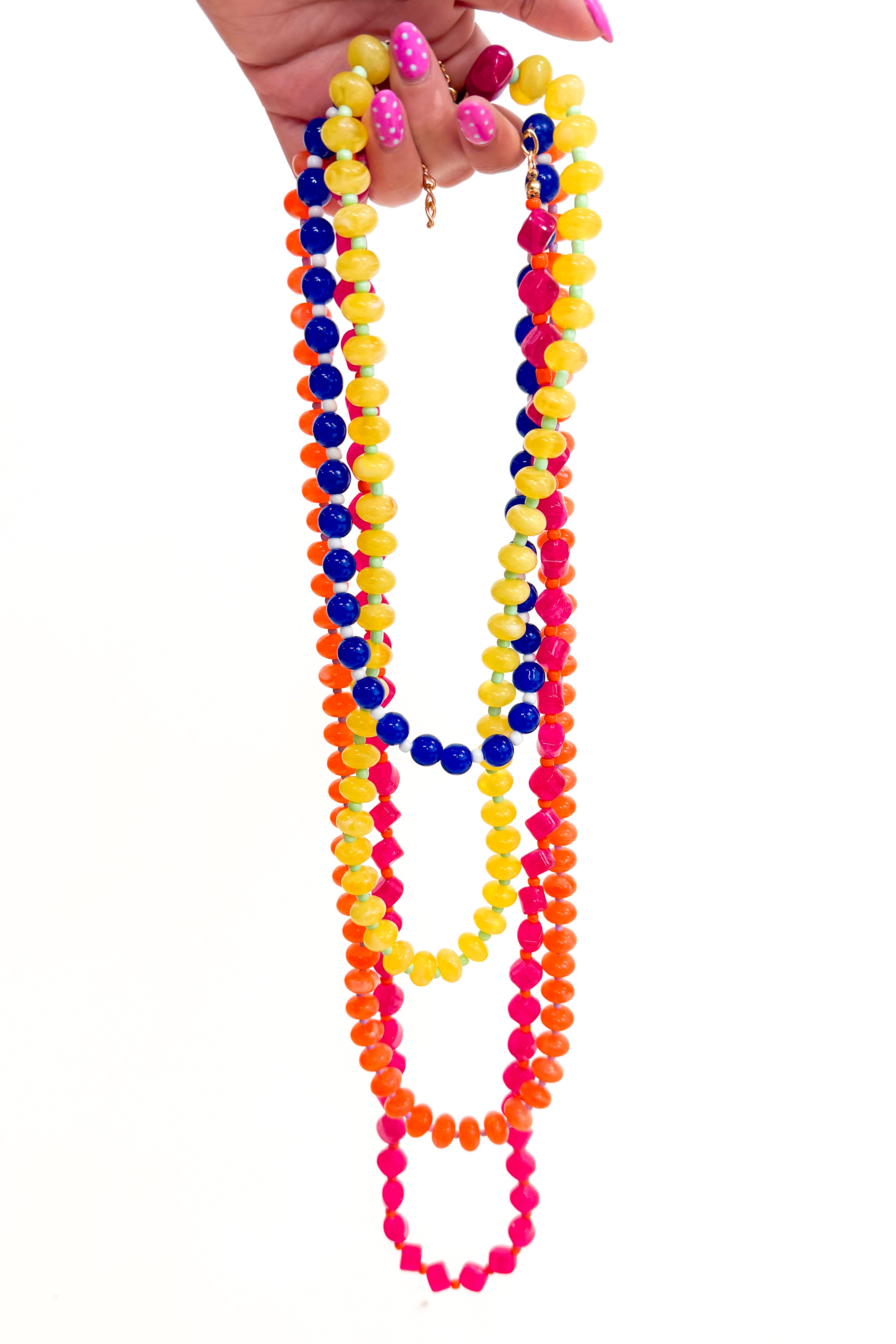 Colorful beaded necklaces held by a hand on a white background