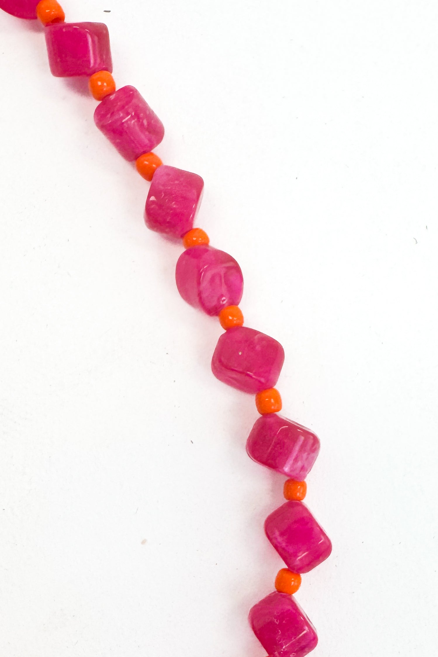 Necklace with pink beads and orange accents on a white background