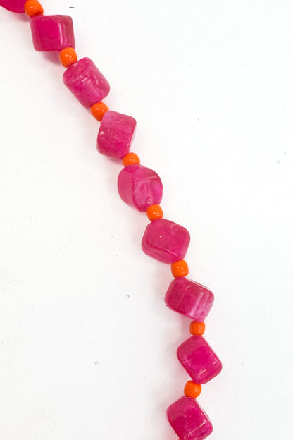 Necklace with pink beads and orange accents on a white background