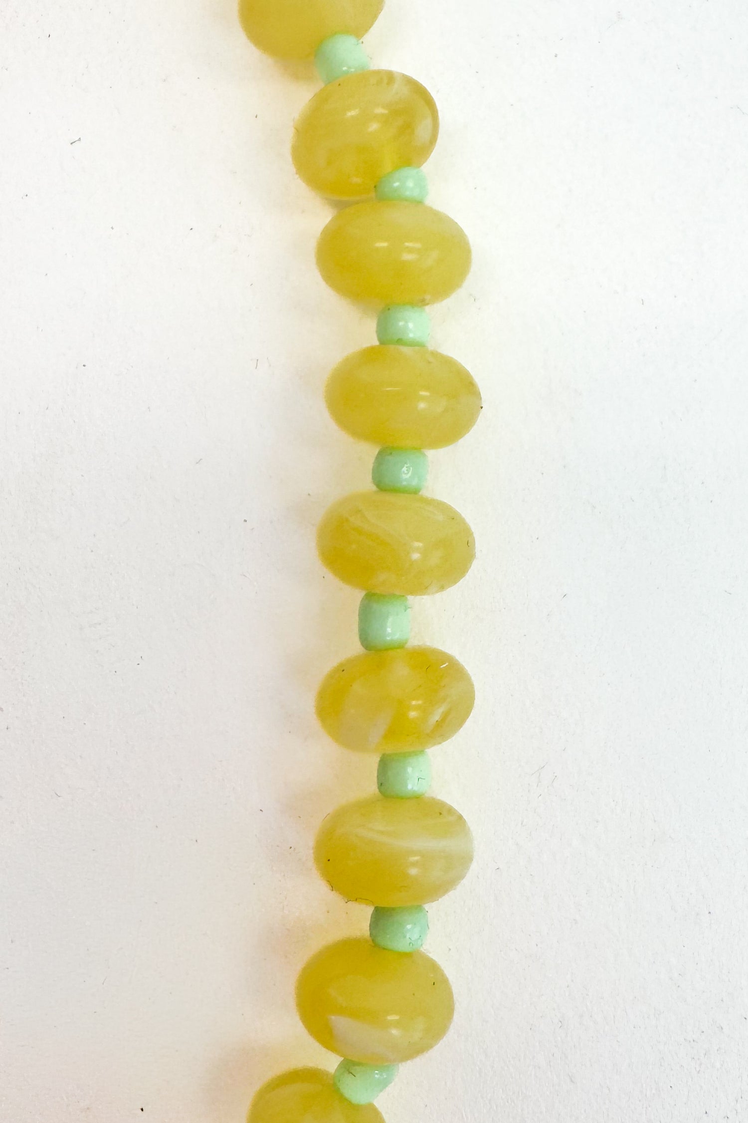 Necklace with green and yellow beads on a white background