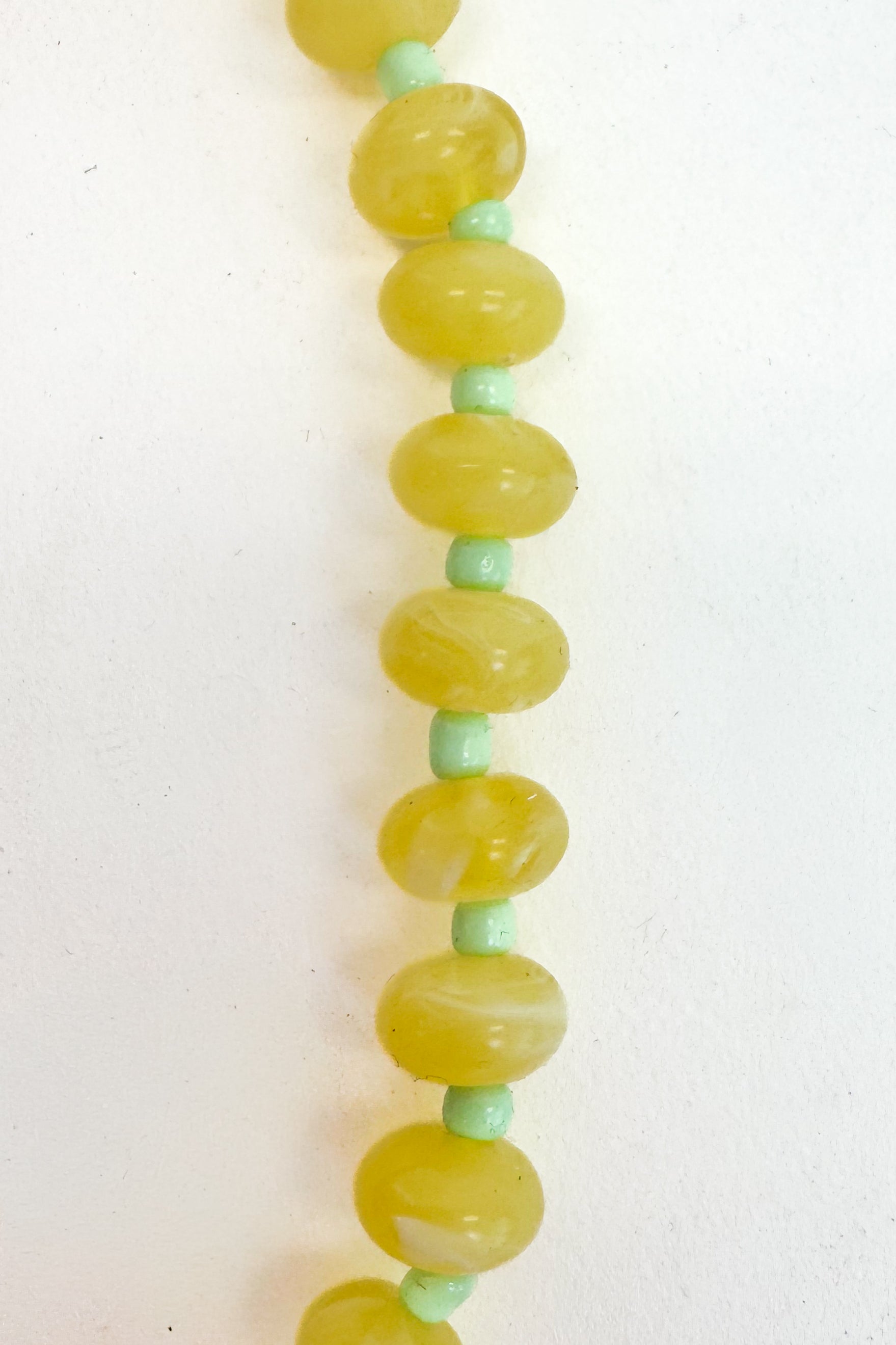 Necklace with green and yellow beads on a white background