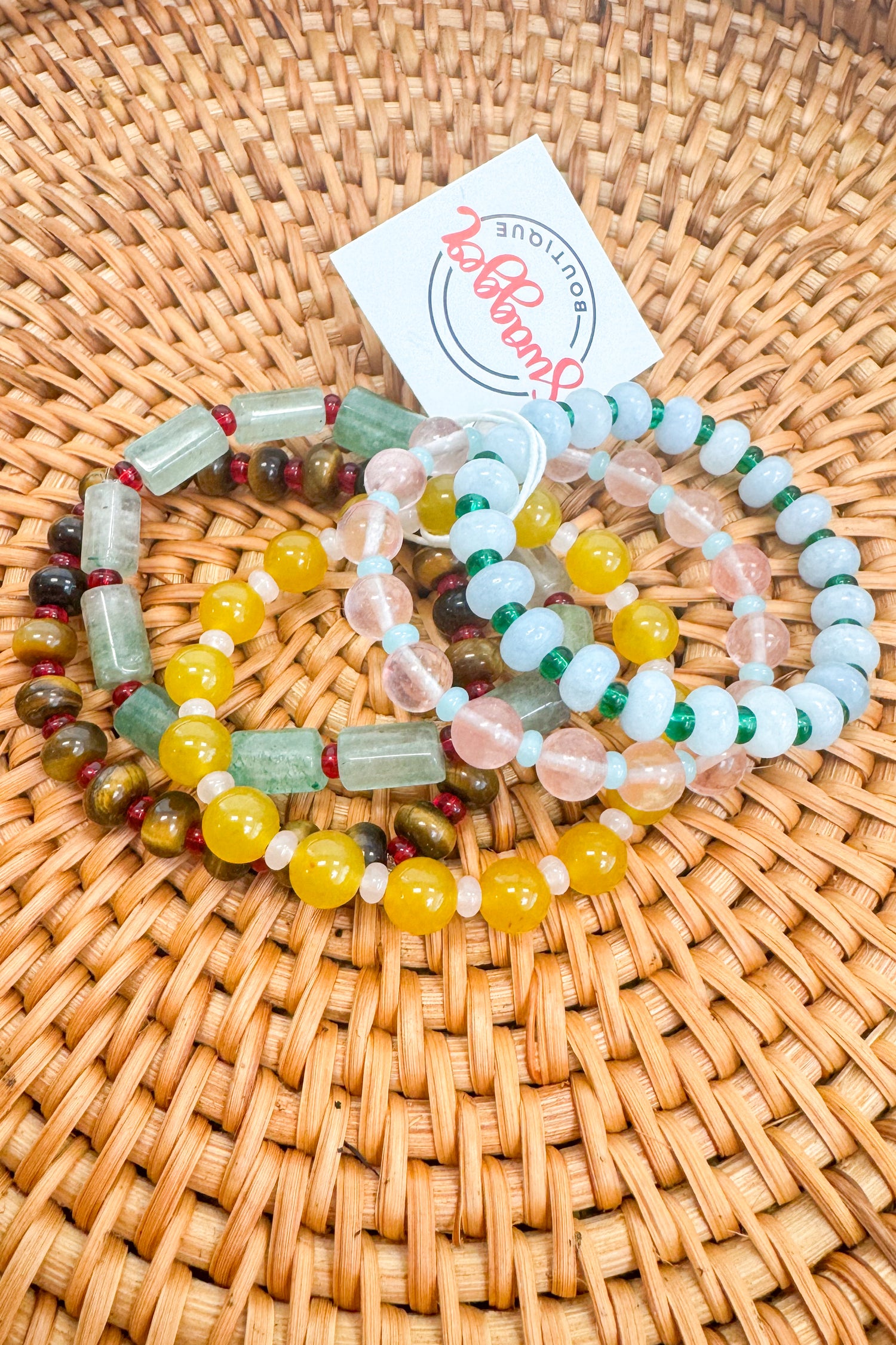 Set of colorful beaded bracelets on a woven surface with a branded card.
