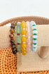 Set of colorful beaded bracelets on a beige fabric with a woven basket background
