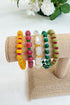 Set of colorful beaded bracelets on a textured surface with flowers in the background