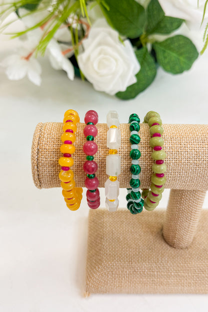 Set of colorful beaded bracelets on a burlap roll with flowers in the background