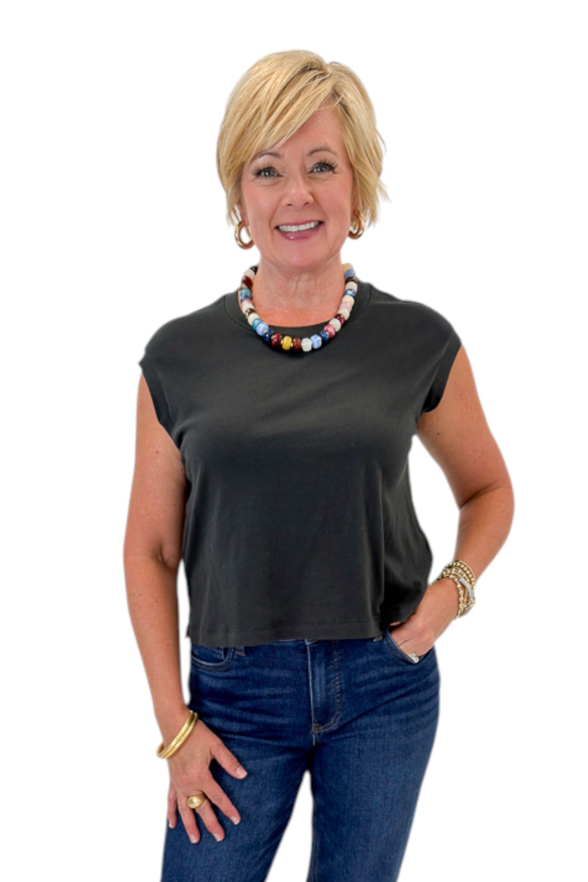 Front view of woman wearing Swagger Boutique’s Ash Black Flex Sleeveless Tee by Z Supply with jeans against white studio background.