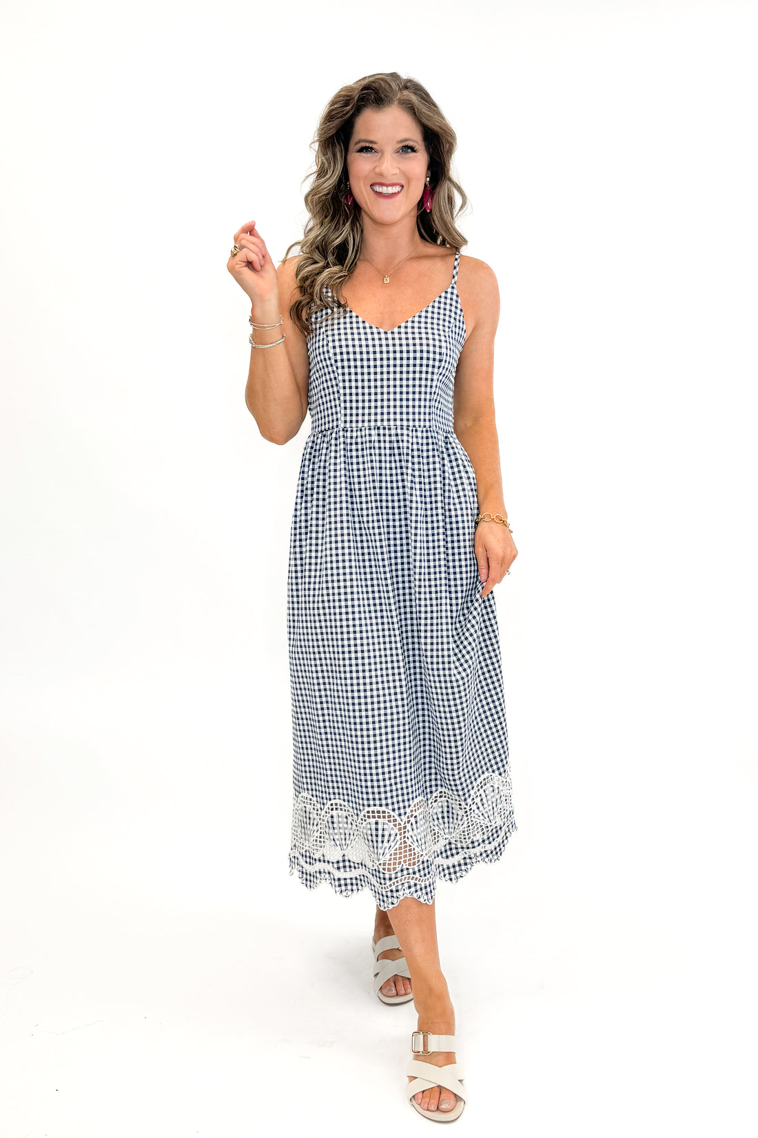 Front view of woman wearing Navy Gingham With Shell Embroidery Dress with sandals against white studio background.