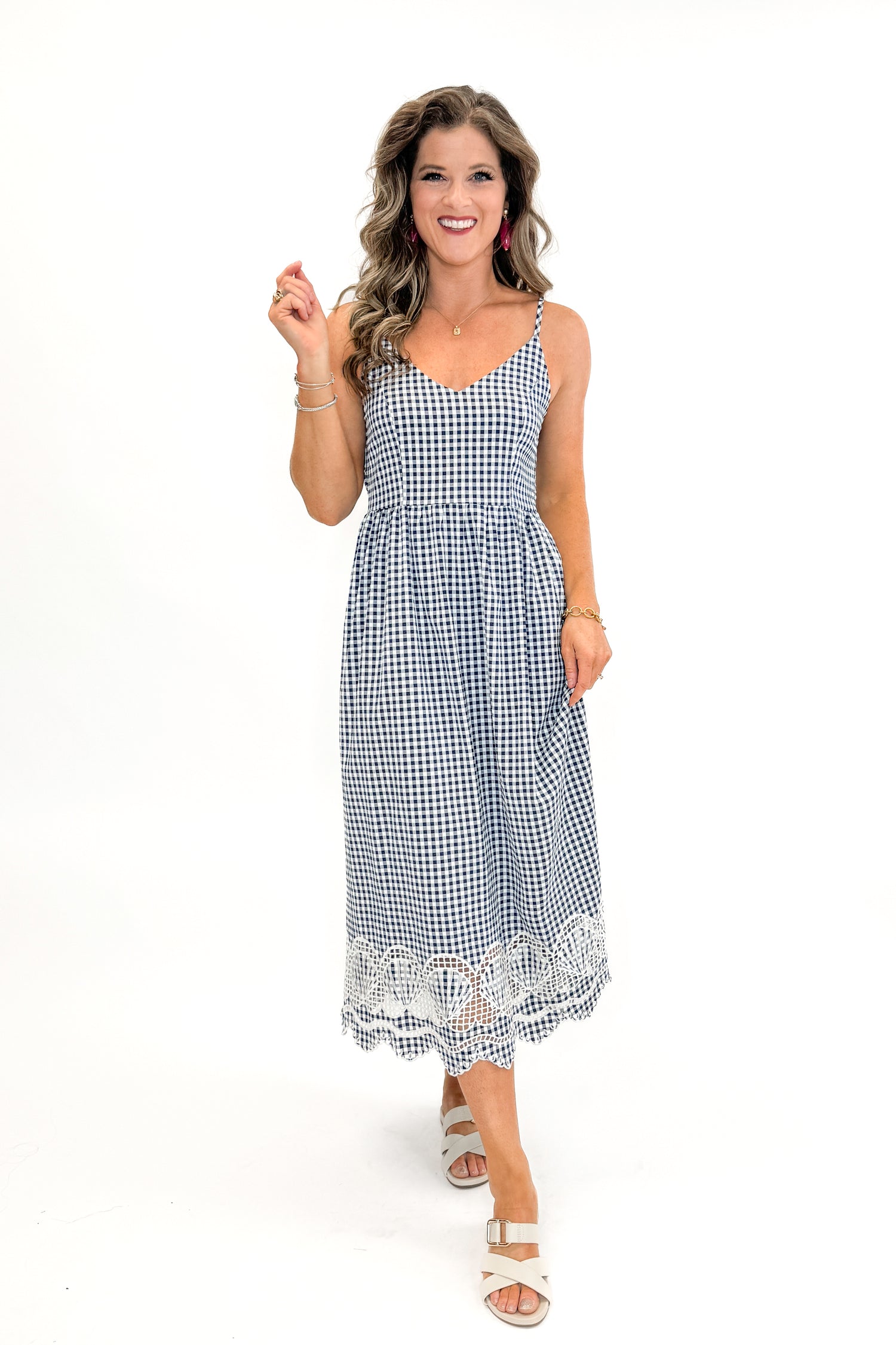 Front view of woman wearing Navy Gingham With Shell Embroidery Dress with sandals against white studio background.