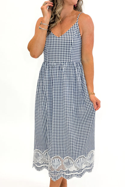 Front view of woman wearing Navy Gingham With Shell Embroidery Dress with sandals against white studio background.