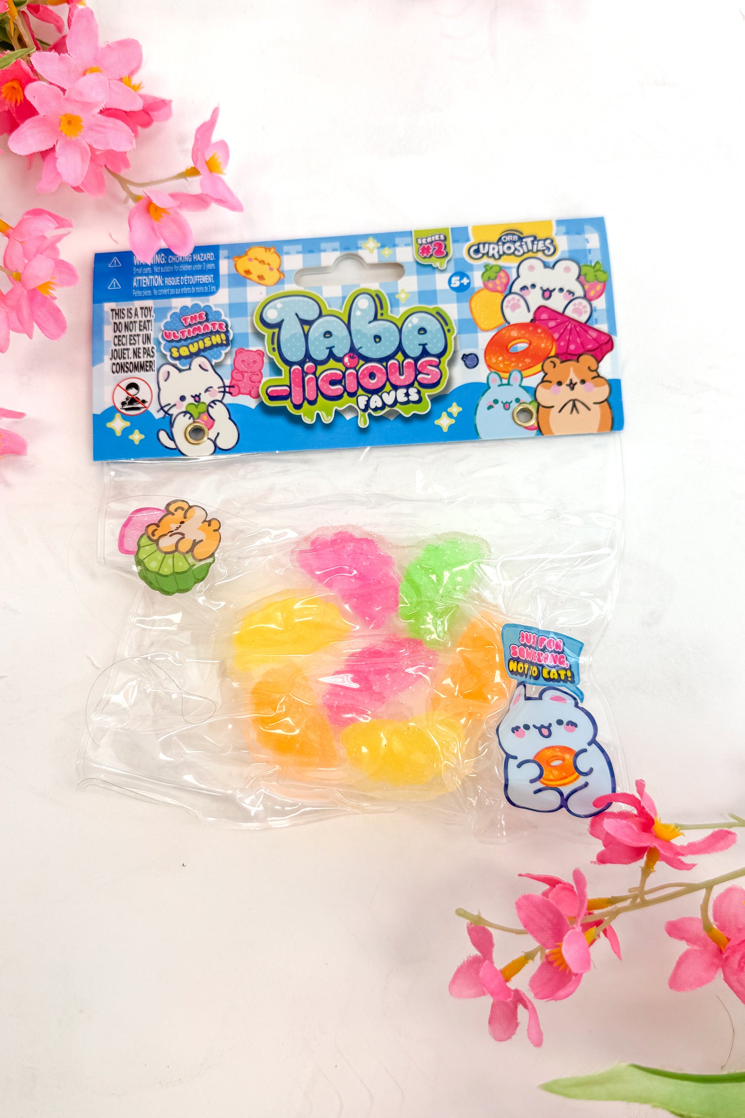 Packaged squeeze toy with colorful packaging on a white background with pink flowers.