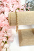 Gold beaded bracelet on a beige fabric with pink flowers in the background