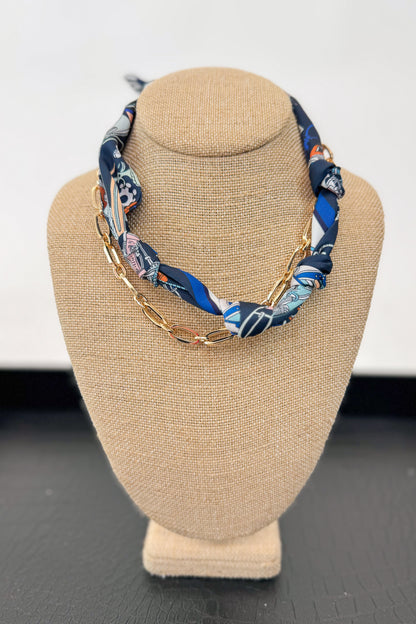 Necklace with blue and white patterned fabric and gold chain on a beige bust