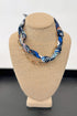 Necklace with blue and white patterned fabric and gold chain on a beige bust