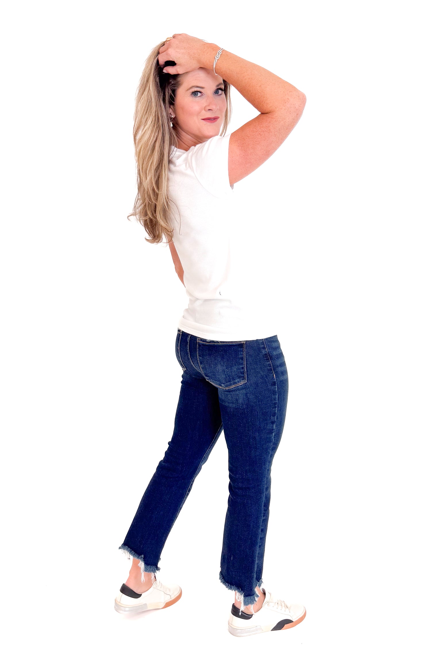 Woman wearing a white top and blue jeans on a white background