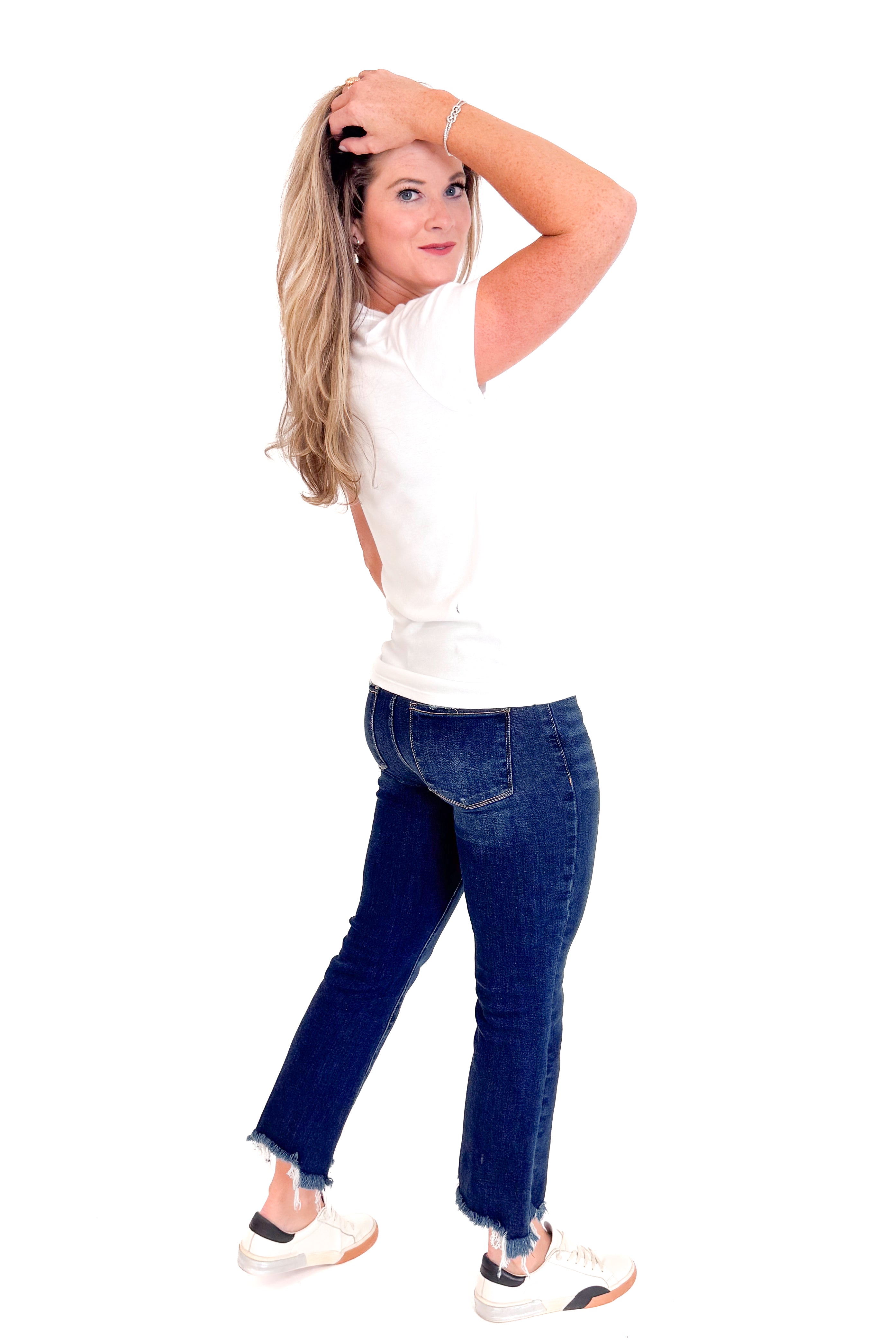 Woman wearing a white top and blue jeans on a white background