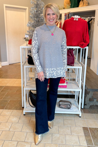 Front view of woman wearing Grey Leopard Print Lined Sweater with jeans at a boutique.