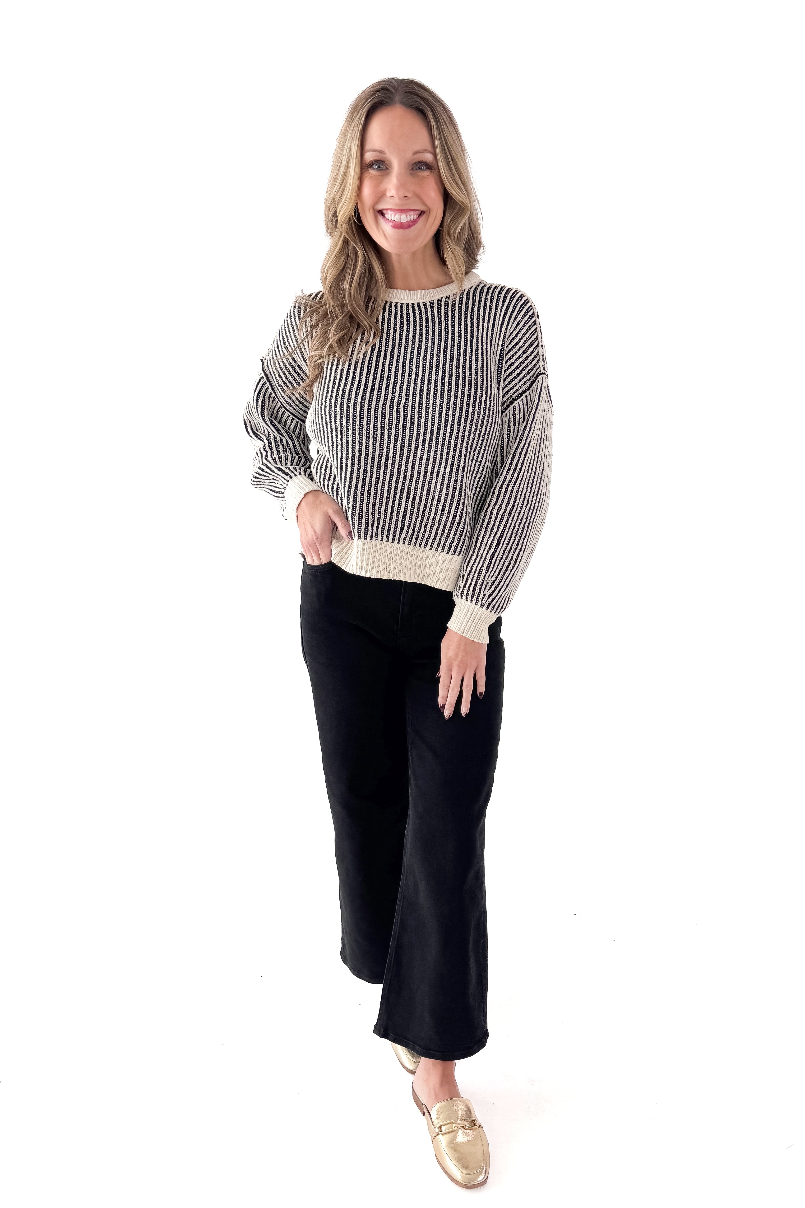 Front view of woman wearing Black &amp; Cream Striped Sweater with jeans against white studio background.