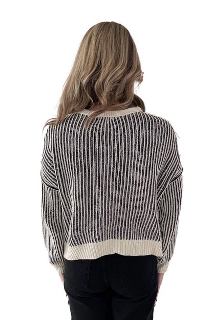 Back view of woman wearing Black &amp; Cream Striped Sweater with jeans against white studio background.