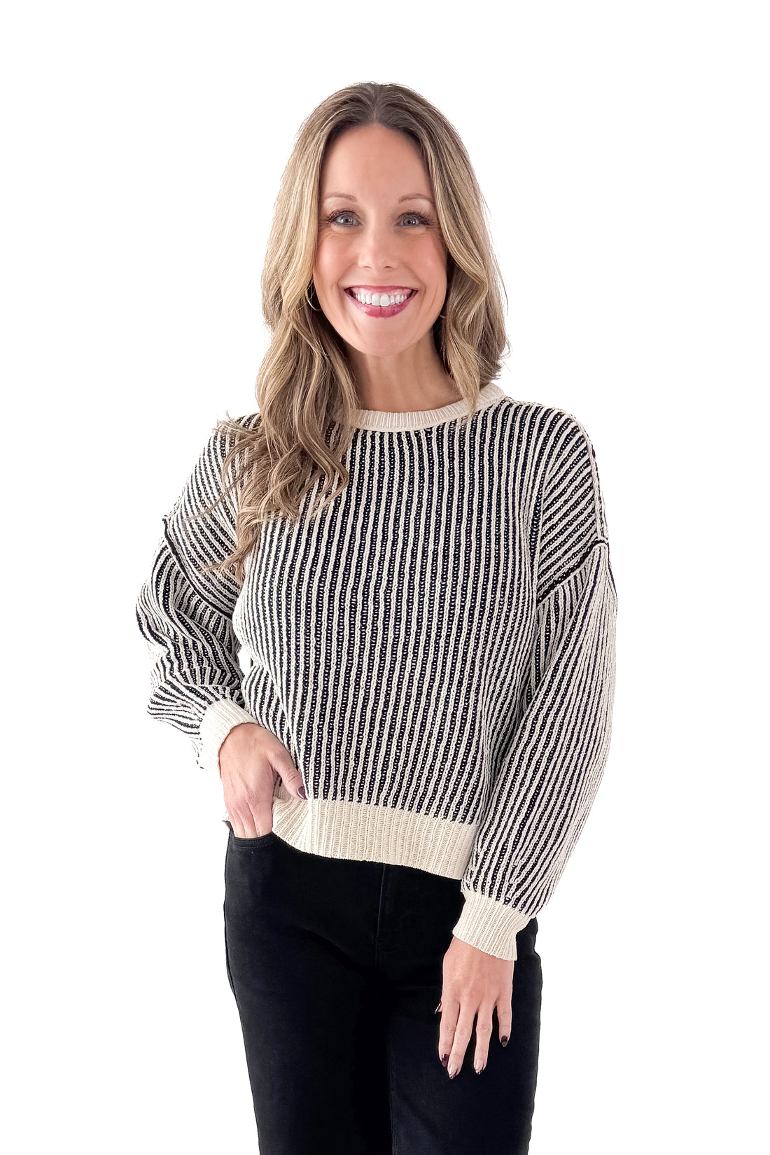 Front view of woman wearing Black &amp; Cream Striped Sweater with jeans against white studio background.
