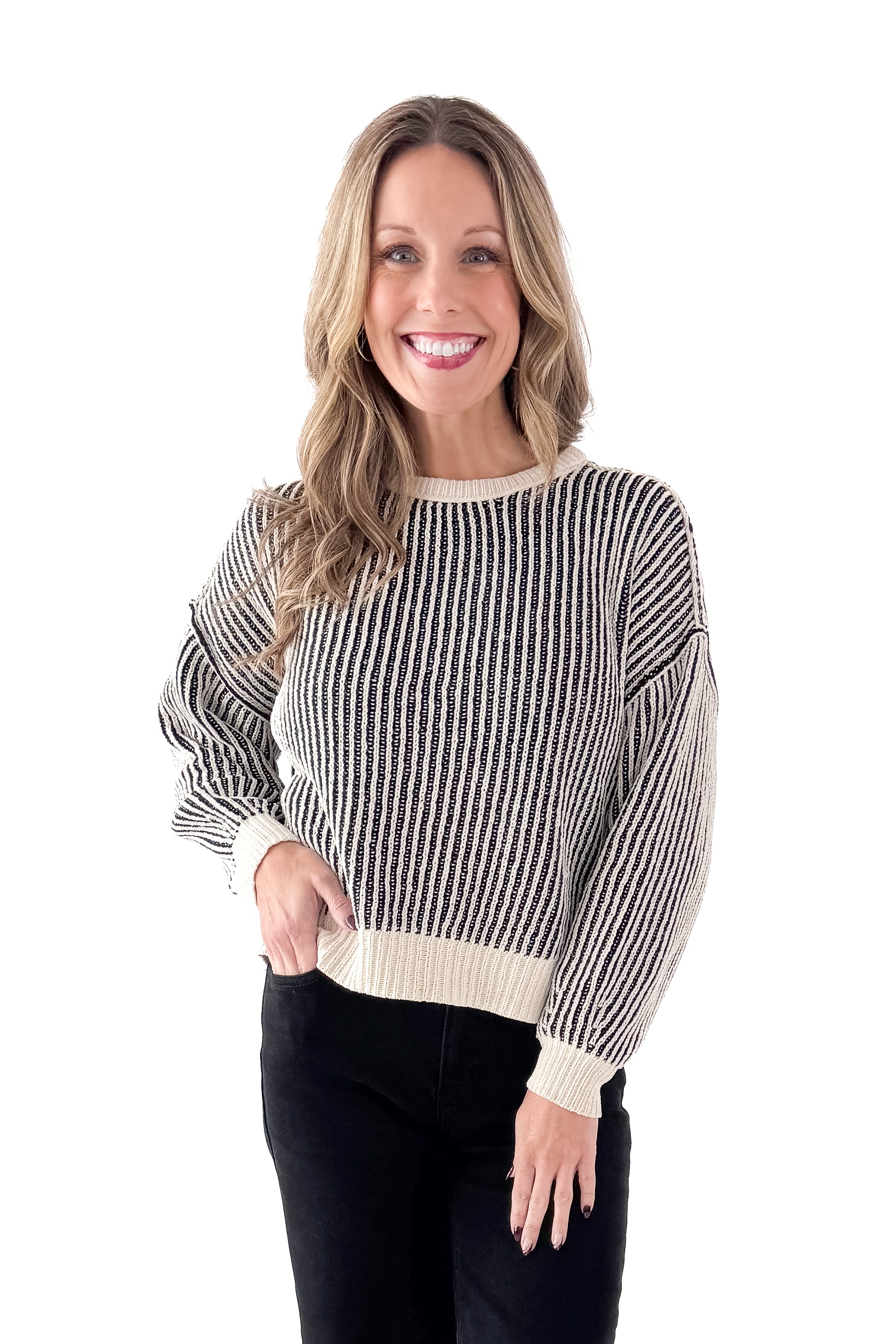 Front view of woman wearing Black &amp; Cream Striped Sweater with jeans against white studio background.